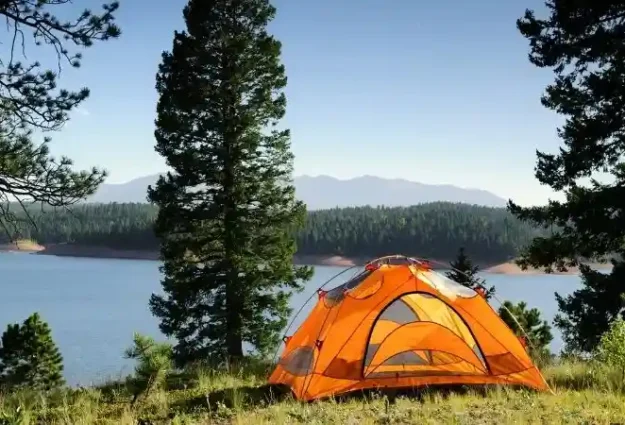 a tent on the grass by a lake